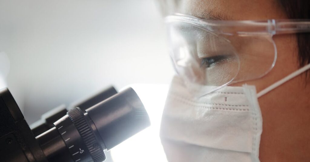 Close-up of a scientist wearing protective gear examining samples in a laboratory setting.